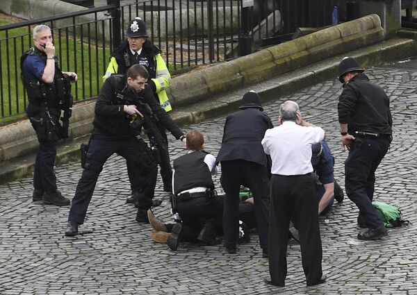 A policeman points a gun at a man on the floor as emergency services attend the scene outside the Palace of Westminster, London, Wednesday, March 22, 2017. A policeman points a gun at a man on the floor as emergency services attend the scene outside the Palace of Westminster, London, Wednesday, March 22, 2017. - Sputnik International