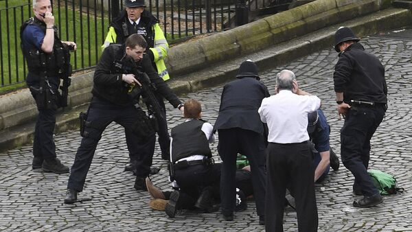 A policeman points a gun at a man on the floor as emergency services attend the scene outside the Palace of Westminster, London, Wednesday, March 22, 2017. - Sputnik International