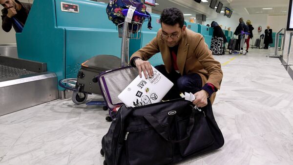 A Libyan traveller packs his laptop in his suitcase before boarding his flight for London at Tunis-Carthage International Airport on March 25, 2017 - Sputnik International