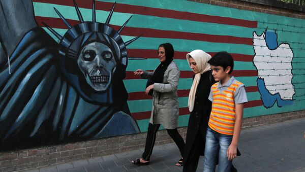 An Iranian family walks past anti-US graffiti on the wall of the former US embassy in Tehran on July 14, 2015 - Sputnik International