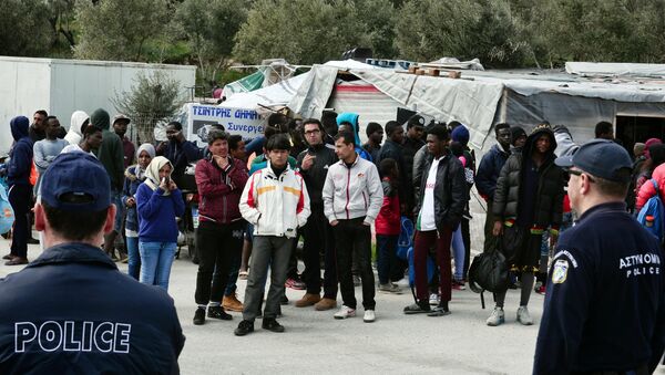 A picture taken on 16 March, 2017 shows policemen standing guard near migrants at the Moria migrant camp on the island of Lesbos, almost a year after an EU-Turkey deal - Sputnik International