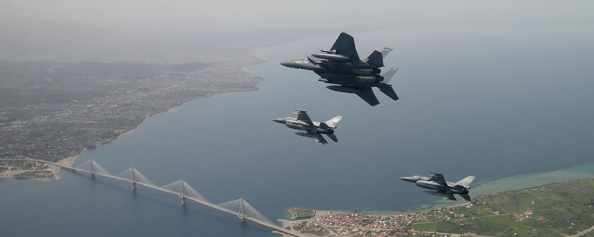 In this photo released by the Hellenic Air Force, two Greek F-16 fighter jets and a USAF F-15E Strike Eagles, based at Lakenheath airbase in England, fly past the 2,880-meter Rio-Antirrio Bridge in southern Greece, on Wednesday, April 13, 2016. The U.S. jets took part in Exercise Iniohos 2016, in southern Greece, together with military aircraft from Greece and Israel.  - Sputnik International, 1920, 23.10.2023