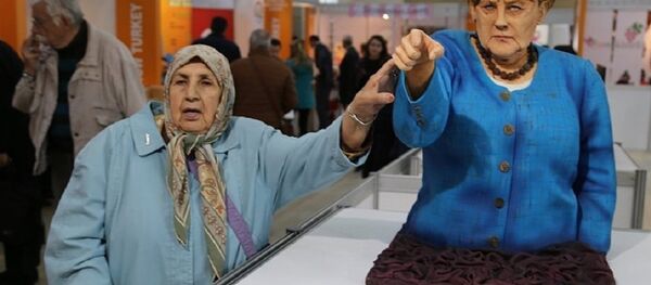A visitor takes a picture next to the cake bust of German Chancellor Angela Merkel by Turkish confectioner Tuba Geçkil at the Festival of Chocolates, Sweets and Cakes in Istanbul. - Sputnik International