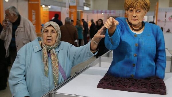 A visitor takes a picture next to the cake bust of German Chancellor Angela Merkel by Turkish confectioner Tuba Geçkil at the Festival of Chocolates, Sweets and Cakes in Istanbul. - Sputnik International