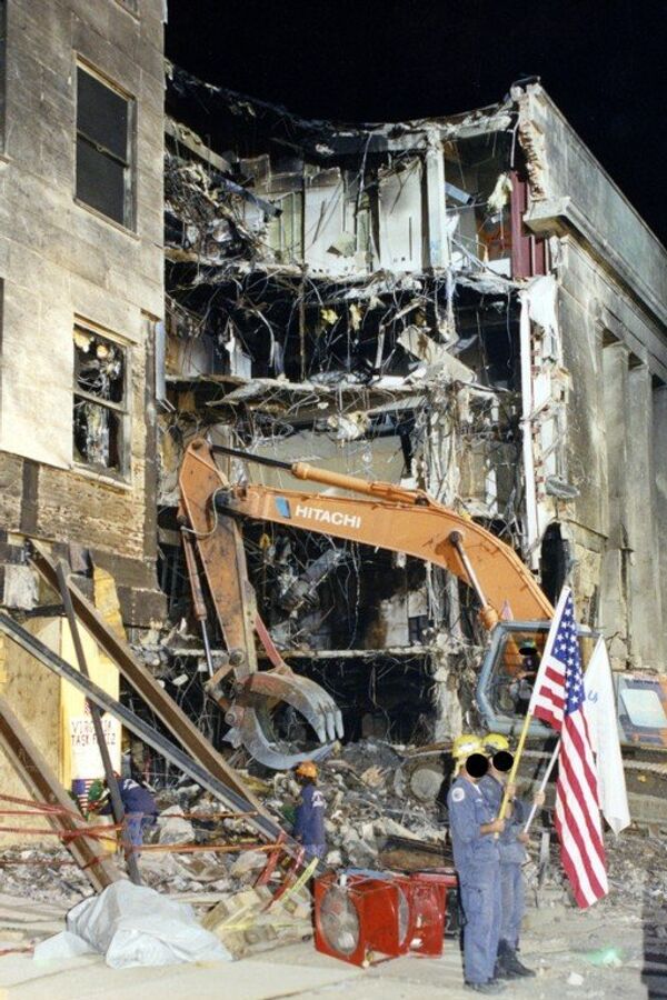 A worker holds up an American flag as a crane excavates through the devastated Pentagon. - Sputnik International