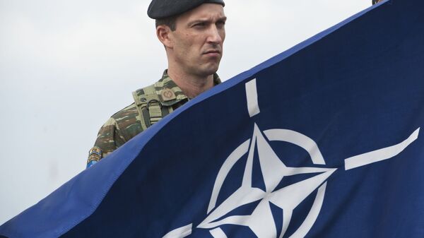 A members of NATO-led peacekeepers in Kosovo (KFOR) holds the NATO flag during the change of command ceremony in Pristina on September 3, 2014 - Sputnik International