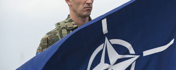 A members of NATO-led peacekeepers in Kosovo (KFOR) holds the NATO flag during the change of command ceremony in Pristina on September 3, 2014 - Sputnik International