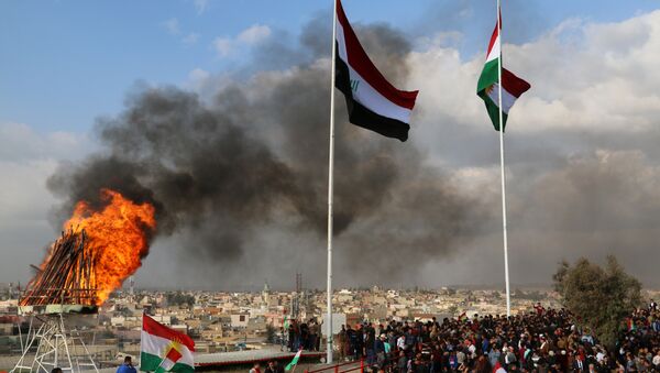 The Kurdish and Iraqi flag sway in the wind as a bonfire burns during the Noruz spring festival celebrations in the northern city of Kirkuk, about 240 kilometres (150 miles) north of Baghdad on March 20, 2017 - Sputnik International