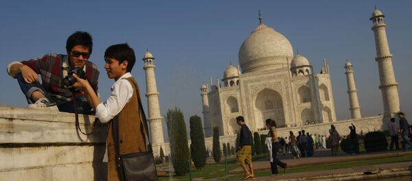 Tourists look at their camera after taking a picture near the UNESCO World Heritage site Taj Mahal in Agra - Sputnik International