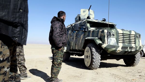 A fighter from the Syrian Democratic Forces, inspects a military vehicle supplied by the US-led coalition, as they gather near a village north-east of Raqa - Sputnik International