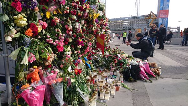 A man takes a picture of flowers on the fence by Ahlens department store following Friday's attack in central Stockholm, Sweden, April 9, 2017 - Sputnik International