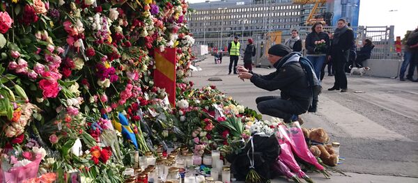 A man takes a picture of flowers on the fence by Ahlens department store following Friday's attack in central Stockholm, Sweden, April 9, 2017 - Sputnik International