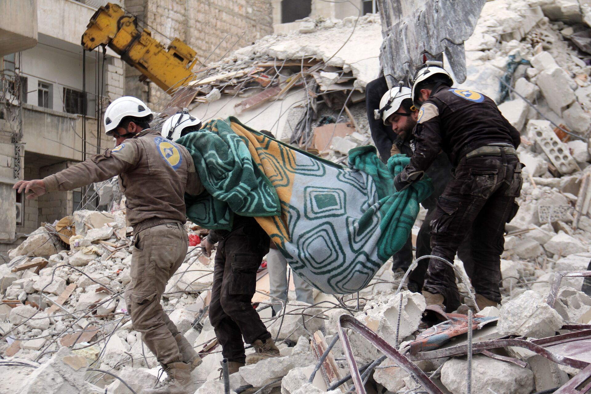 Syrian civil defence volunteers, known as the White Helmets, carry a body retrieved from the rubble following reported government airstrike on the Syrian town of Ariha, in the northwestern province of Idlib, on February 27, 2017 - Sputnik International, 1920, 15.04.2022