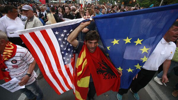A protestor holds the flags of the United States, Macedonia, Albania and the European Union while attending a march through downtown Skopje, Macedonia, Monday, April 18, 2016 - Sputnik International