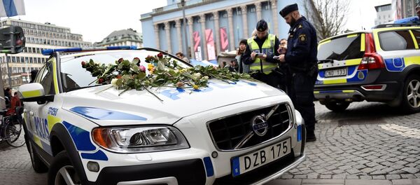 Flowers lay on a police car at Hotorget square near the crime scene in central Stockholm on April 8, 2017, the day after a hijacked beer truck plowed into pedestrians on Drottninggatan and crashed into Ahlens department store, killing four people, injuring 15 others - Sputnik International