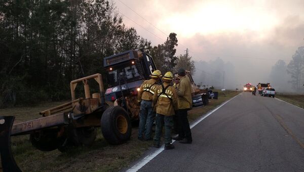Firefighters and firefighting equipment arrive to deal with wildfire that quickly spread across acres of land, damaging many homes and forcing residents to evacuate in this image released on social media in Nassau County, Florida, U.S. on March 22, 2017 - Sputnik International