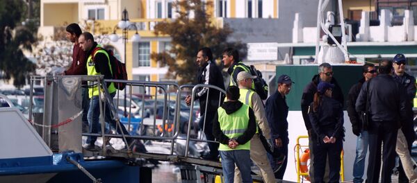 Frontex officials and Greek police escort migrants aboard a Turkish boat heading to Turkey from the port of Mytilene on the Greek island of Lesbos on October 21, 2016 - Sputnik International
