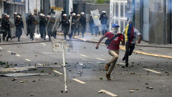 Demonstrators run away during a rally against Venezuela's President Nicolas Maduro's government in Caracas, Venezuela April 10, 2017 - Sputnik International