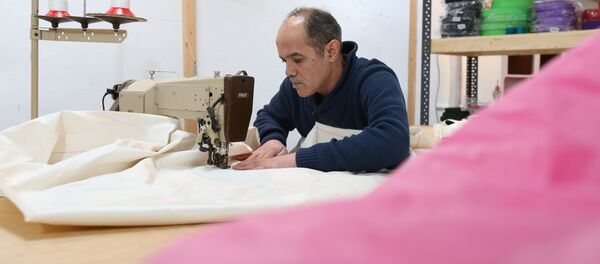 Syrian refugee Mohammed Alsahani used to make curtains in Damascus and now works with the sailmaker Coastworxx near the port of Kiel in Germany. - Sputnik International