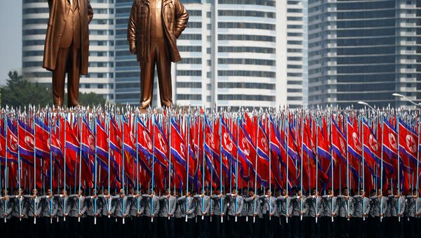 People carry flags in front of statues of North Korea founder Kim Il Sung (L) and late leader Kim Jong Il during a military parade marking the 105th birth anniversary Kim Il Sung, in Pyongyang April 15, 2017. - Sputnik International