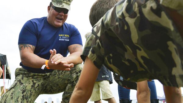 Chief Petty Officer Joseph Schmidt III, assigned to the Navy SEAL and SWCC Scout Team, encouraging a young fan to do pushups at the 2016 Stuart Air Show in Stuart, Fla. - Sputnik International