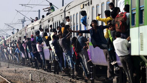 Indian passengers hang onto a train as it departs from a station on the outskirts of New Delhi on February 28, 2017 - Sputnik International