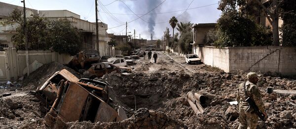 An Iraqi forces member stands next to a crater made by an air strike in west Mosul as Iraqi troops continue battling against Islamic State (IS) group fighters to further advance inside the city, on March 7, 2017 - Sputnik International