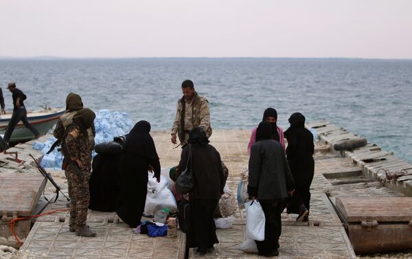 Syrian Democratic Forces (SDF) fighters relocate people that fled from Raqqa city on the bank of the Euphrates river, west of Raqqa city, Syria April 8, 2017 - Sputnik International