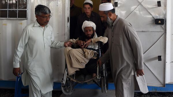 Afghan refugees help a disabled refugee at the United Nations High Commissioner for Refugees (UNHCR) repatriation centre on the outskirts of Peshawar on April 11, 2017, as they prepare to return to their home country after fleeing civil war and Taliban rule - Sputnik International