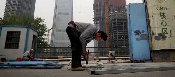 In this Sunday, April 16, 2017 photo, a worker assembles an aluminum platform outside a construction site at the Central Business District of Beijing - Sputnik International