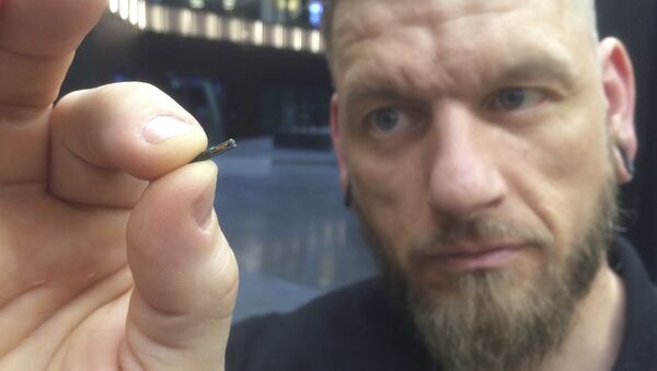 Self-described “body hacker” Jowan Osterlund from Biohax Sweden, holds a small microchip implant, similar to those implanted into workers at the Epicenter digital innovation business centre during a party at the co-working space in central Stockholm, Tuesday March 14, 2017 - Sputnik International