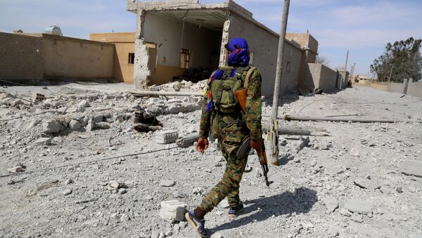 A member of the US-backed Syrian Democratic Forces (SDF), made up of an alliance of Arab and Kurdish fighters, patrols in the town of Al-Karamah, 26 kms from the Islamic State (IS) group bastion of Raqa, as they advance to encircle the jihadists, on March 26, 2017 - Sputnik International