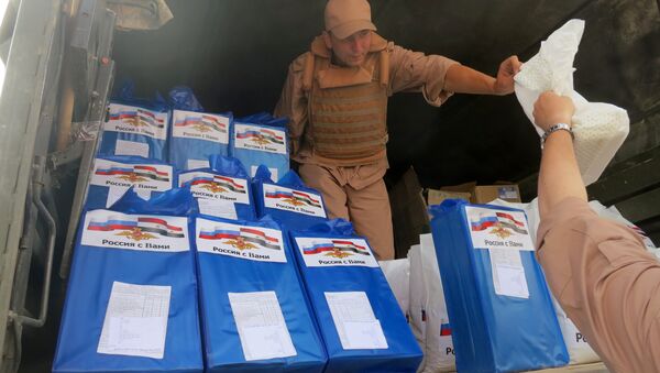 (File) A picture taken during a press tour organized by the Russian Army shows a Russian soldier distributing food parcels on April 8, 2016 in al-Qaryatain, a town in the province of Homs in central Syria, a few days after Syrian regime forces seized it from jihadists of the Islamic State (IS) group - Sputnik International