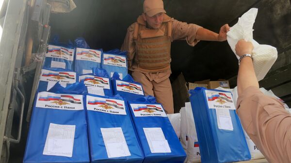 (File) A picture taken during a press tour organized by the Russian Army shows a Russian soldier distributing food parcels on April 8, 2016 in al-Qaryatain, a town in the province of Homs in central Syria, a few days after Syrian regime forces seized it from jihadists of the Islamic State (IS) group - Sputnik International
