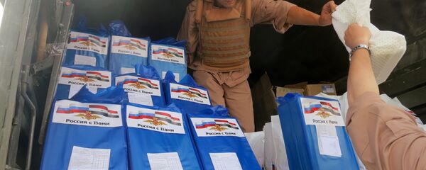 (File) A picture taken during a press tour organized by the Russian Army shows a Russian soldier distributing food parcels on April 8, 2016 in al-Qaryatain, a town in the province of Homs in central Syria, a few days after Syrian regime forces seized it from jihadists of the Islamic State (IS) group - Sputnik International