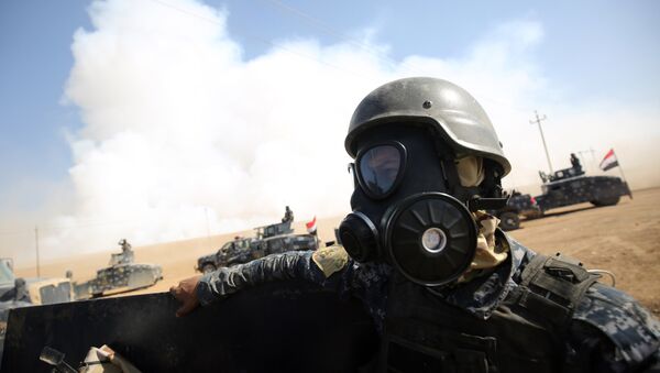 Iraqi forces wear gas masks for protection as smoke billows in the background after Islamic State (IS) group jihadists torched Mishraq sulphur factory, near the Qayyarah base, about 30 kilometres south of Mosul, during an operation to retake the main hub city from IS on October 22, 2016 - Sputnik International