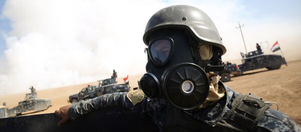 Iraqi forces wear gas masks for protection as smoke billows in the background after Islamic State (IS) group jihadists torched Mishraq sulphur factory, near the Qayyarah base, about 30 kilometres south of Mosul, during an operation to retake the main hub city from IS on October 22, 2016 - Sputnik International