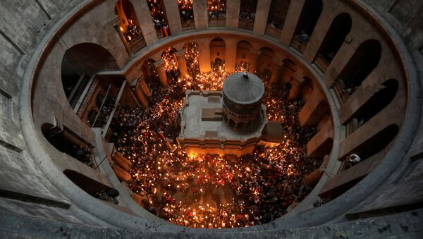Верующие со свечами во время сошествия благодатного огня в Храм Гроба Господня в Иерусалиме - Sputnik International
