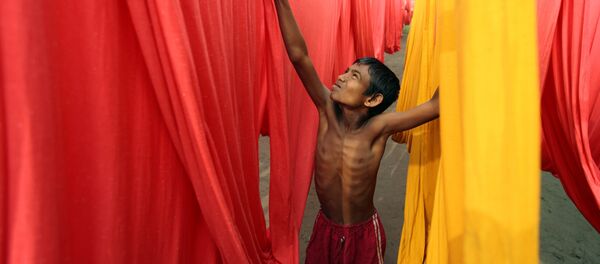 In this Saturday, Dec. 22, 2012 file photo, a Bangladeshi child works at a clothes-dyeing factory in Narayanganj, outskirts of Dhaka, Bangladesh. In this Saturday, Dec. 22, 2012 file photo, a Bangladeshi child works at a clothes-dyeing factory in Narayanganj, outskirts of Dhaka, Bangladesh. - Sputnik International