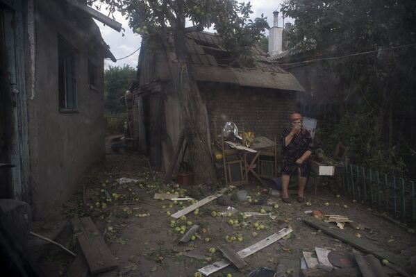 A local woman is sitting near a house which was destroyed during a shelling by Ukrainian military forces. - Sputnik International