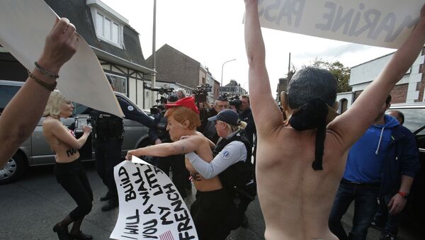 Femen activists, ones wearing the mask of Marine Le Pen, left, and U.S President Donald Trump, center, are detained as they demonstrate in Henin Beaumont, northern France, where far-right leader and presidential candidate Le Pen will vote, during the first round of the French presidential election - Sputnik International