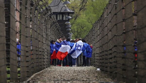 People walk between barb wire fences in the former Nazi death camp of Auschwitz as thousands of people, mostly youth from all over the world, gather for the annual March of the Living during Holocaust Remembrance Day in Oswiecim, Poland April 24, 2017. - Sputnik International