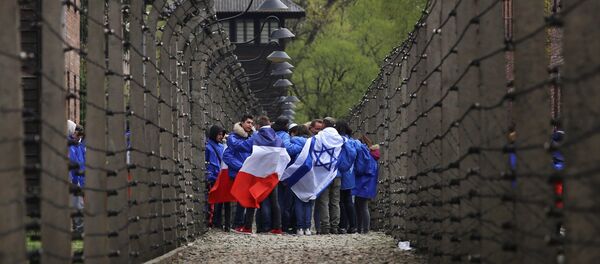 People walk between barb wire fences in the former Nazi death camp of Auschwitz as thousands of people, mostly youth from all over the world, gather for the annual March of the Living during Holocaust Remembrance Day in Oswiecim, Poland April 24, 2017. - Sputnik International
