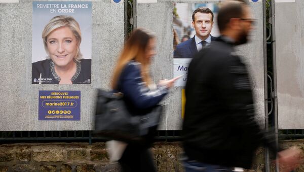 People walk past campaign posters of Marine Le Pen (L), French National Front (FN) political party leader, and Emmanuel Macron (R), head of the political movement En Marche! (Onwards!), two of the eleven candidates who run in the 2017 French presidential election in Paris, France, April 10, 2017 - Sputnik International