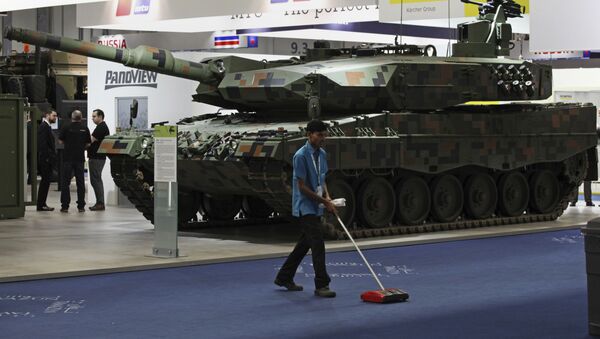 A cleaner sweeps the floor in front of a Rheinmetall MBT tank at the International Defense Exhibition and Conference, known by the acronym IDEX, in Abu Dhabi, United Arab Emirates, Sunday, Feb. 19, 2017 - Sputnik International