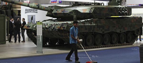 A cleaner sweeps the floor in front of a Rheinmetall MBT tank at the International Defense Exhibition and Conference, known by the acronym IDEX, in Abu Dhabi, United Arab Emirates, Sunday, Feb. 19, 2017 - Sputnik International