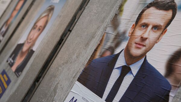 People walk past campaign posters of Emmanuel Macron (L), head of the political movement En Marche! (Onwards!), and Marine Le Pen (R), French National Front (FN) political party leader, two of the eleven candidates who run in the 2017 French presidential election, are seen in Paris, France, April 10, 2017 - Sputnik International