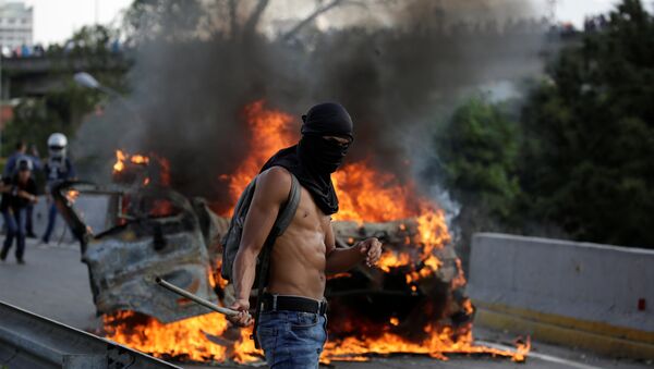 A demonstrator stands near fire during a rally against Venezuela's President Nicolas Maduro in Caracas, Venezuela April 24, 2017 - Sputnik International