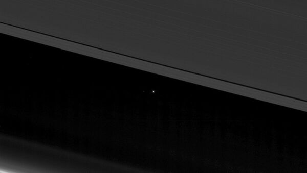 NASA image shows planet Earth and the moon, center left, as small points of light behind the rings of Saturn, captured by the Cassini spacecraft, 870 million miles (1.4 billion kilometers) away from Earth - Sputnik International
