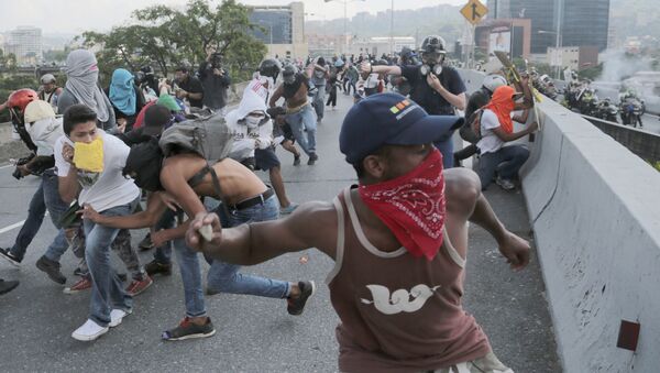 Anti-government protesters throw stones from a highway overpass at a passing police patrol in Caracas, Venezuela, Monday, April 24, 2017 - Sputnik International